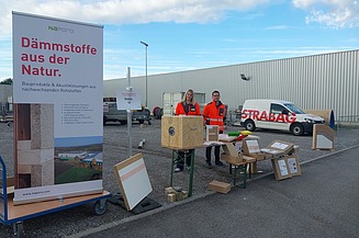 Dieses Bild zeigt uns hinter unserem Stand. Auf diesem sind unserer Produkte ausgestellt und links daneben steht ein Roll Up