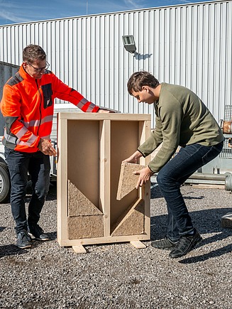 Schüler beim Einbau einer Dämmung in die Holzständerwand