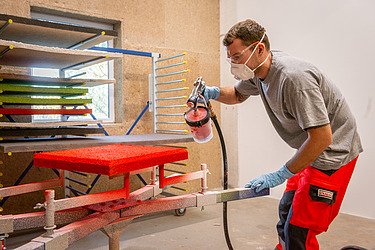 Mitarbeiter beschichtet Akustikplatten