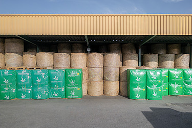 Bild zeigt ein Lager von Laporo mit Rundballen und davor fertig verpackte Ballen 