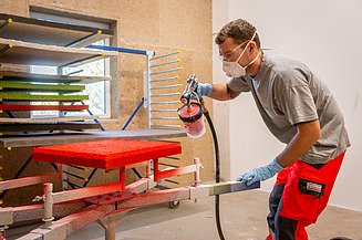 Beschichtung Zu Sehen ist ein Mitarbeiter der Firma Naporo der gerade ein Wall Field mit roter Farbe besprüht