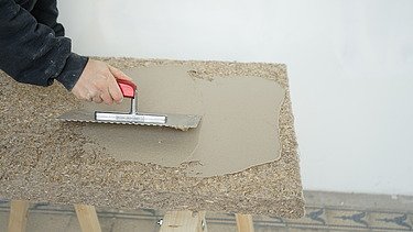 Auf diesem Bild wird gerade Muschelkalk auf eine Putzträgerplatte von Naporo aufgetragen