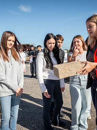 STRABAG Mitarbeiterin die den Kindern erklärt was eine Schnittseite ist