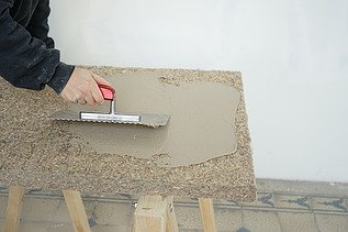 Auf diesem Bild wird gerade Muschelkalk auf eine Putzträgerplatte von Naporo aufgetragen