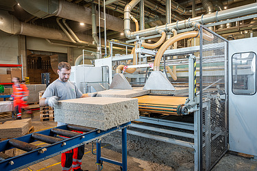 Bild zeigt Mitarbeiter der Platten am Fließband stapelt