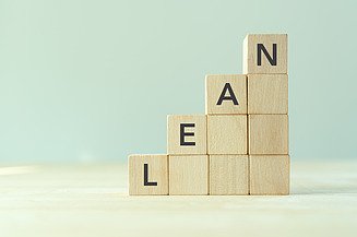 Auf diesem Bild sind einzelne Holzwürfel abgebildet, welche zu einer Treppe gestapelt sind. Auf den obersten steht das Wort LEAN.